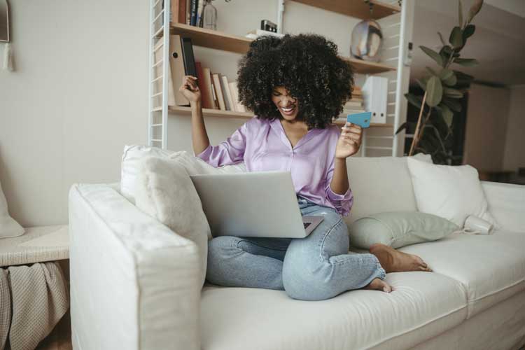 Happy woman with credit card doing online shopping on laptop at home